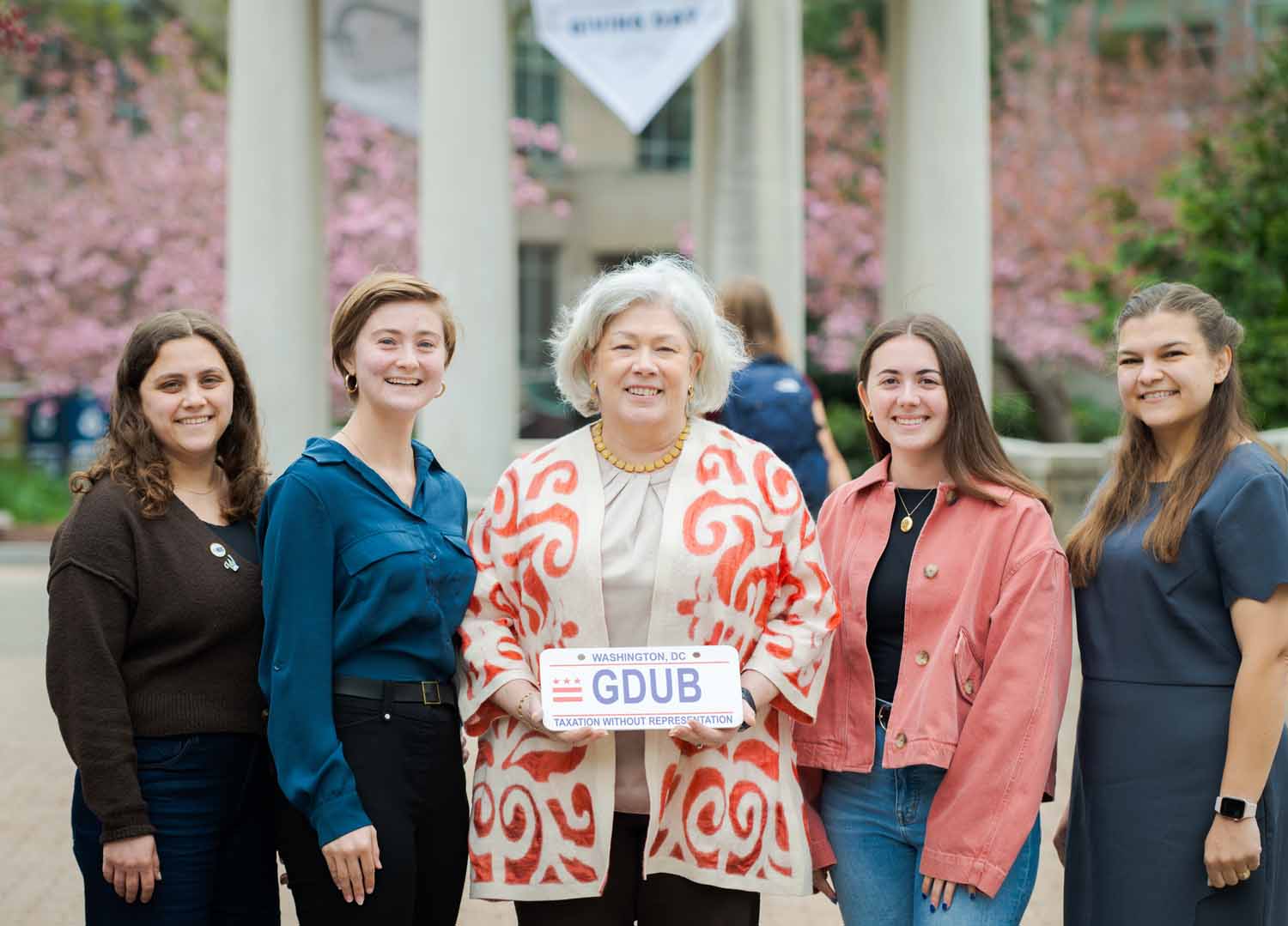 Four people pose with President Ellen Granberg on Giving Day 2025. President Granberg is holding a DC license plate that says "GDUB"