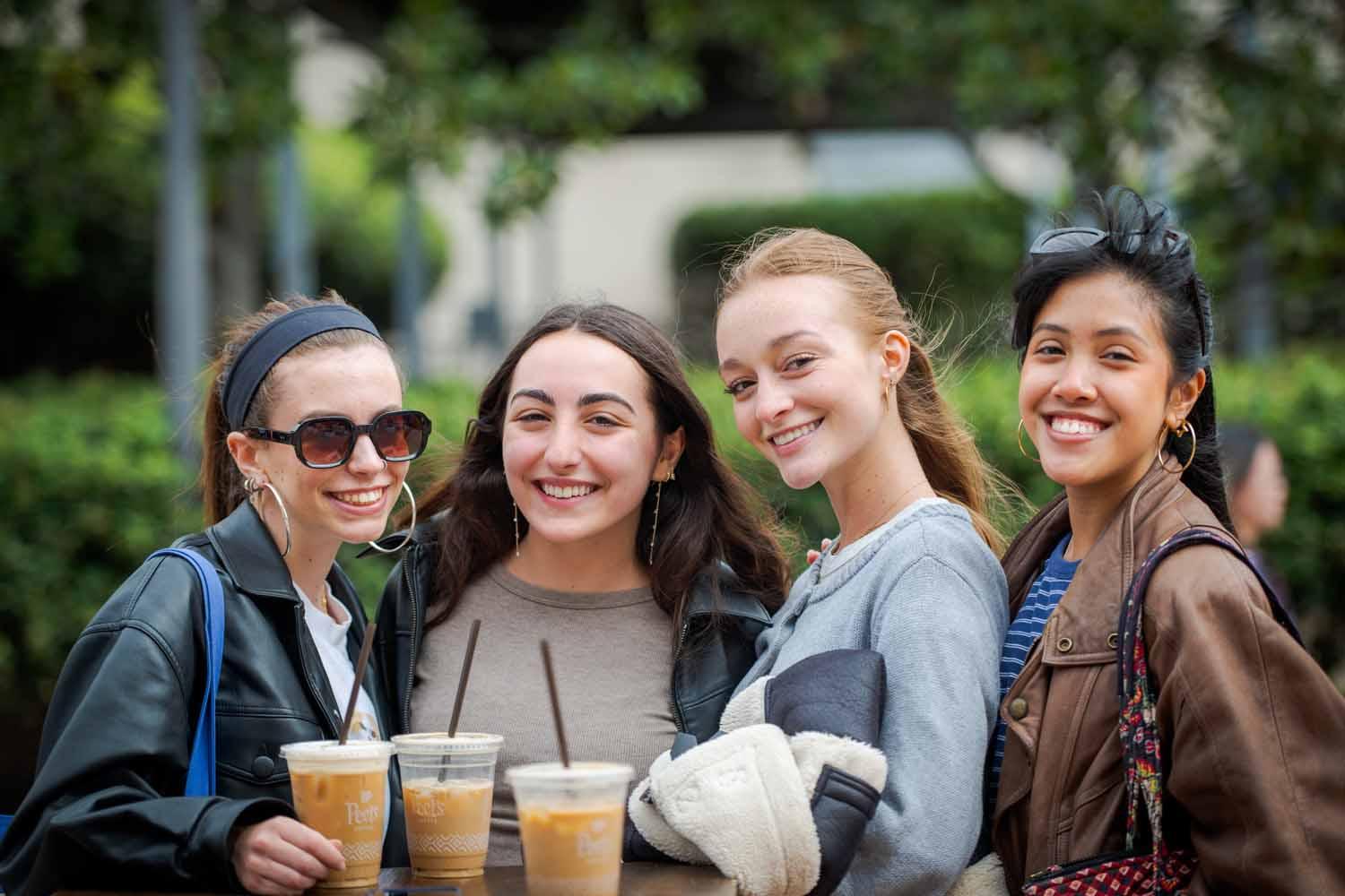 Four women pose with iced coffee on Giving Day 2025